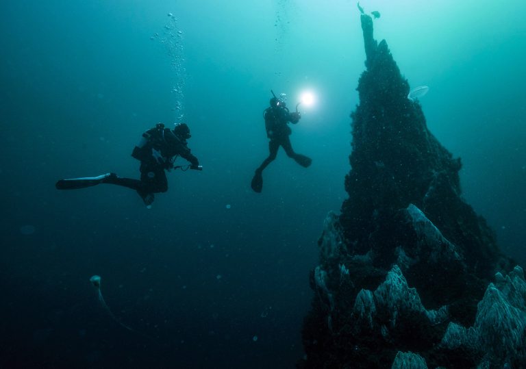 "PADI Deep Diver student descending along a sloping reef wall at 38 meters"