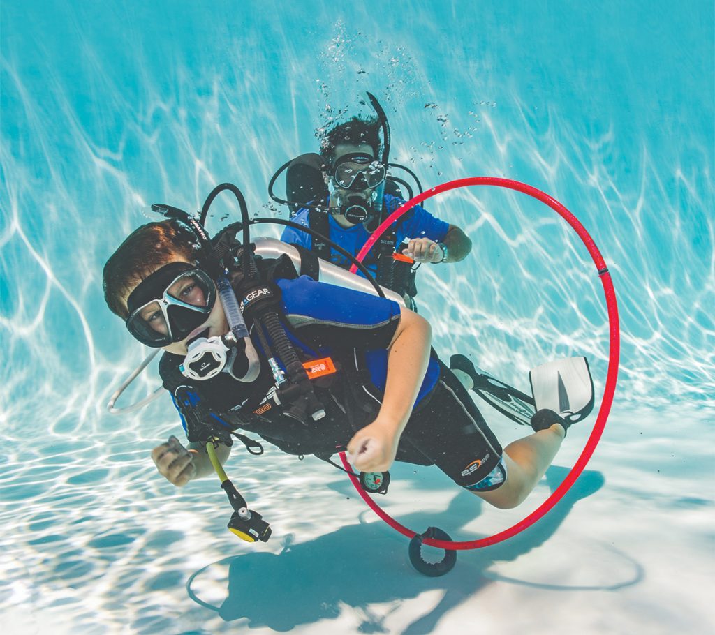 Child blowing bubbles underwater with scuba gear during PADI Bubblemaker