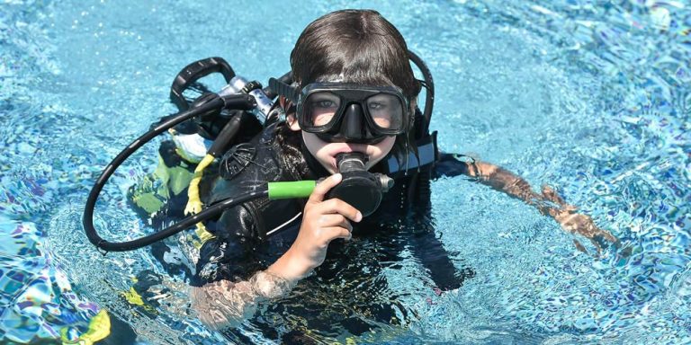 Child learning scuba skills with instructor in Phuket pool
