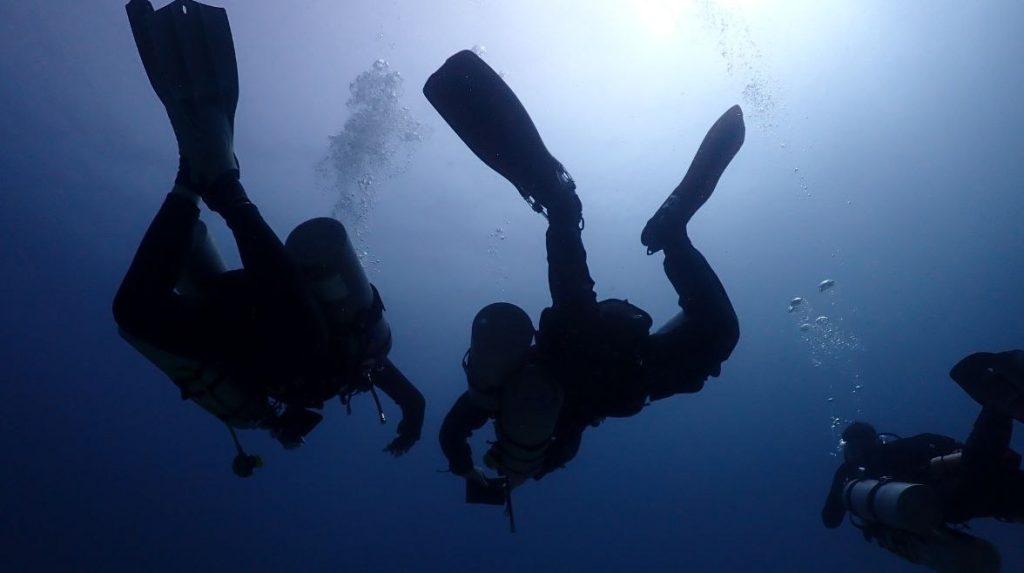 Two technical divers with twin tanks exploring a shipwreck, promoting PADI TecRec courses