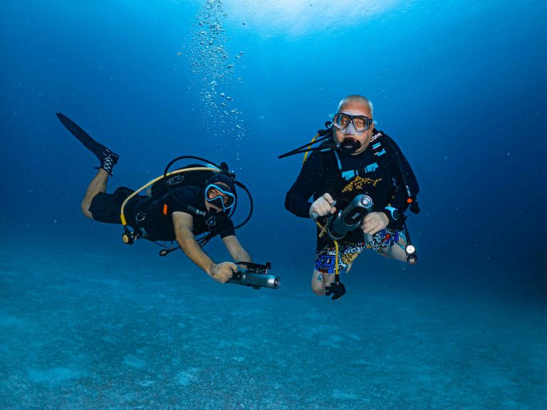 Two divers cruising side-by-side on scooters