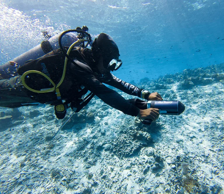 Dive instructor guiding student through DPV training session in open water.